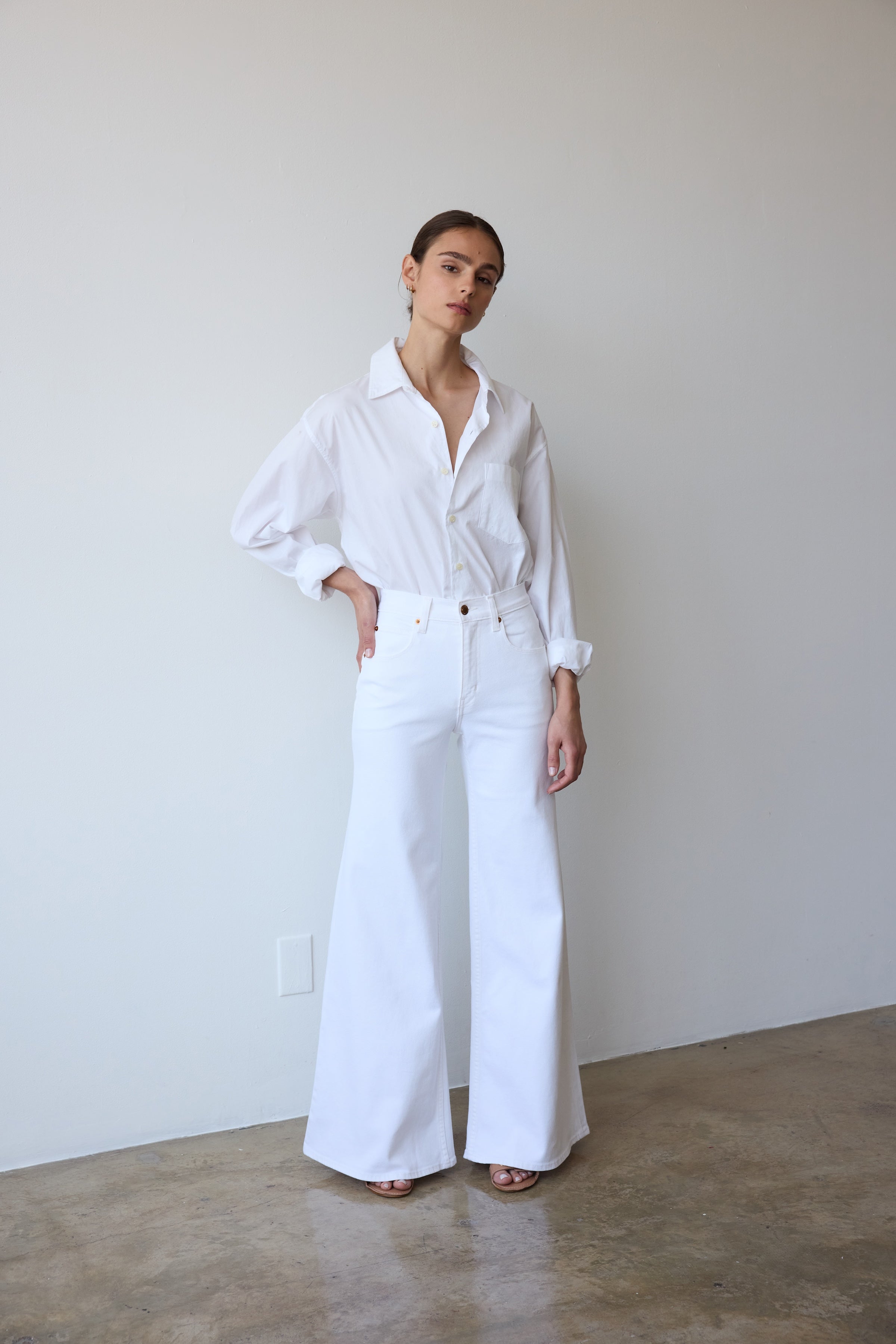 Person wearing a white outfit standing against a plain wall.