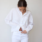 Person wearing a white shirt and white pants against a plain background