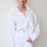 Person wearing a white shirt and pants against a plain background