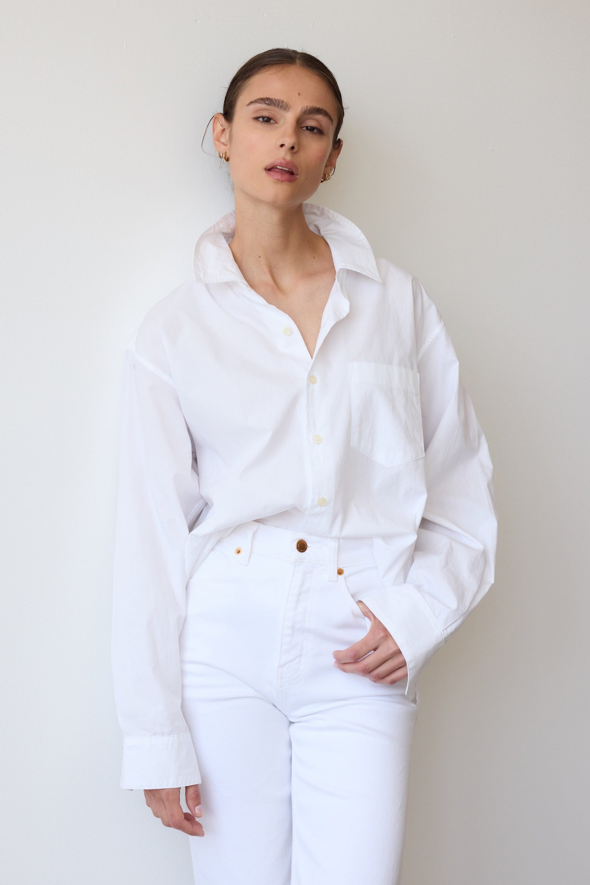 Person wearing a white shirt and pants against a plain background
