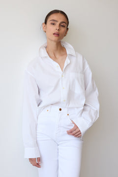 Person wearing a white shirt and pants against a plain background