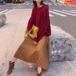 a woman sitting on a rock in the street wearing a red sweater