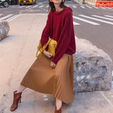 a woman sitting on a rock in the street wearing a red sweater