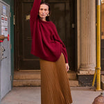 a woman in a read sweater standing on a box on the sidewalk
