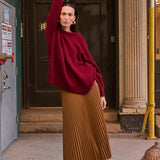 a woman in a read sweater standing on a box on the sidewalk
