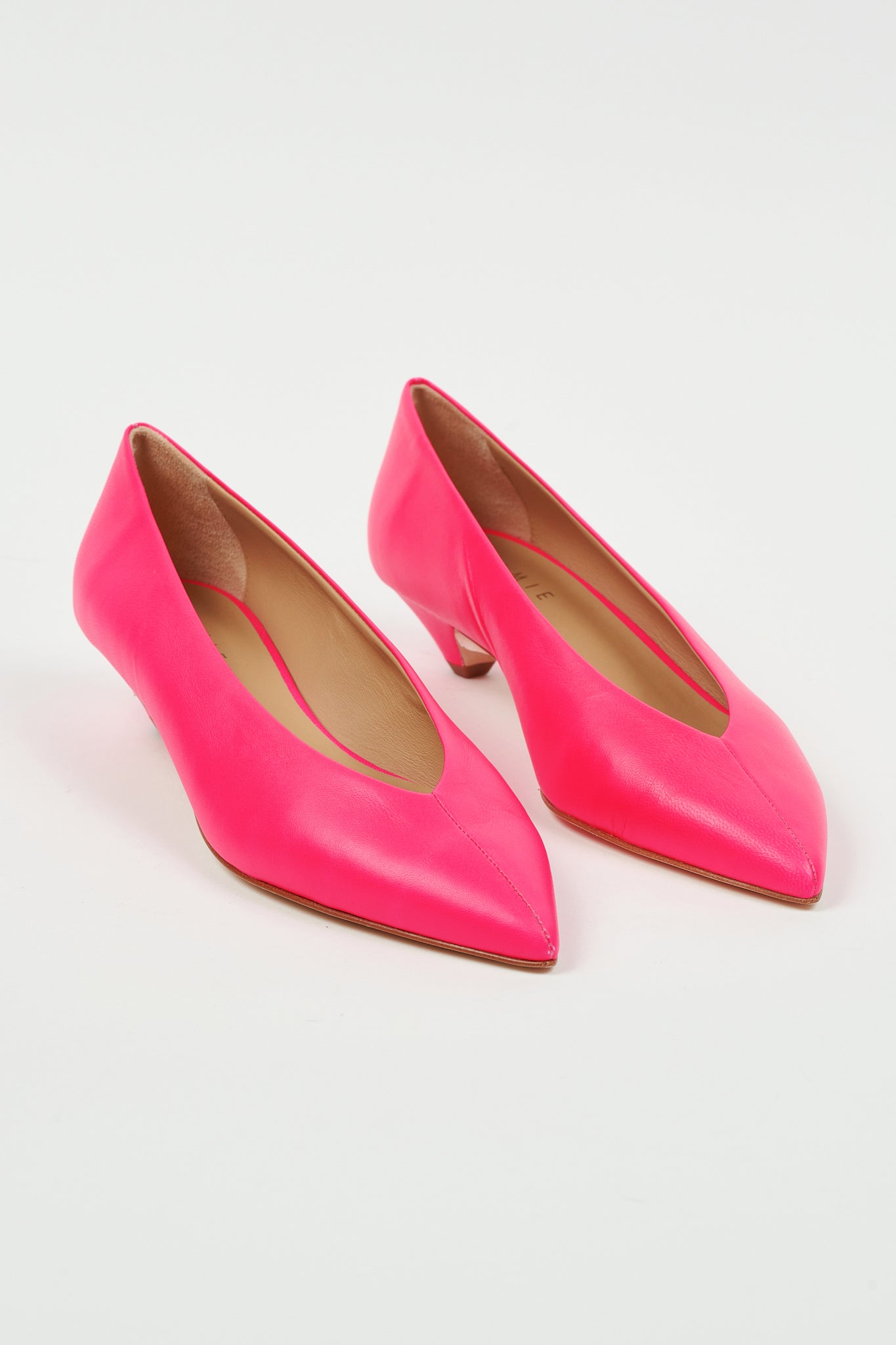 A pair of bright pink leather pointed-toe pumps with kitten heels, displayed on a clean white background.
