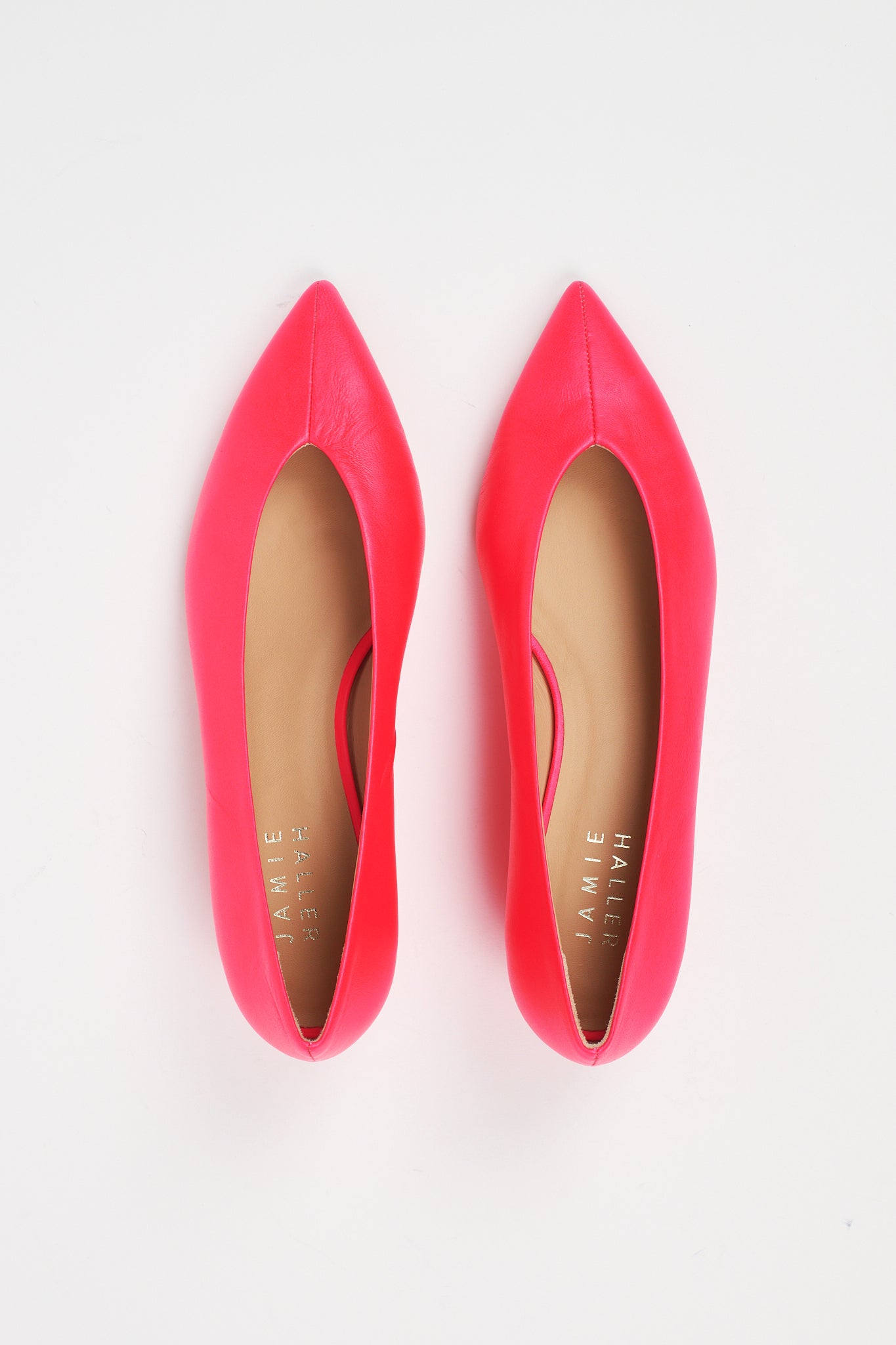 A pair of bright pink pointed-toe flats with tan insoles, photographed from a top-down view on a white background. The brand name 'JAMIE HANLEY' is printed on the insole.